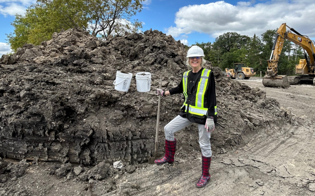 Construction worker with buckets on muddy site.