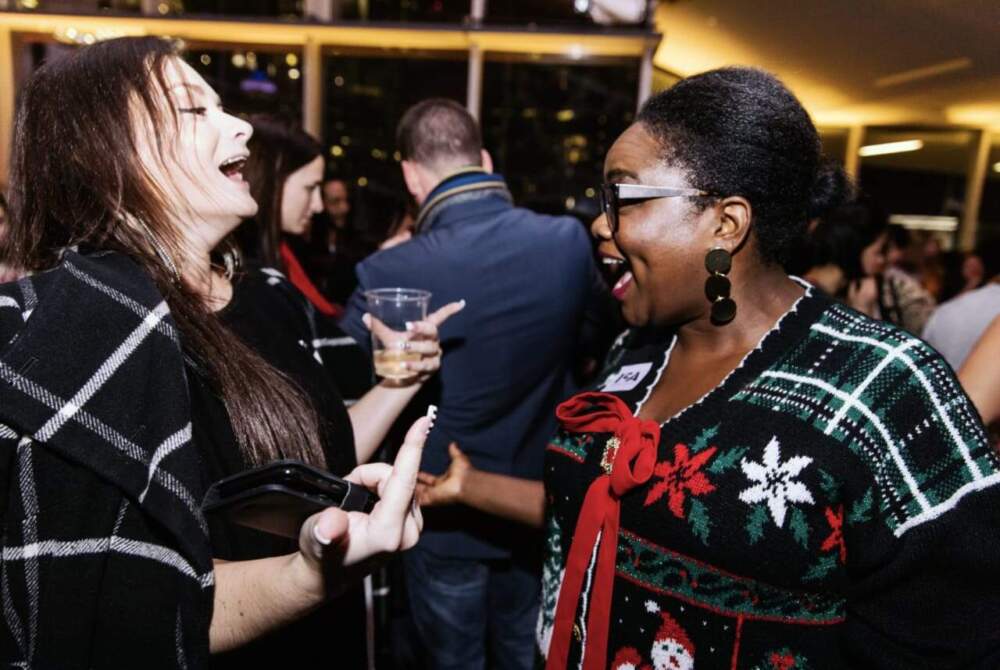 Two women laughing at a holiday party.