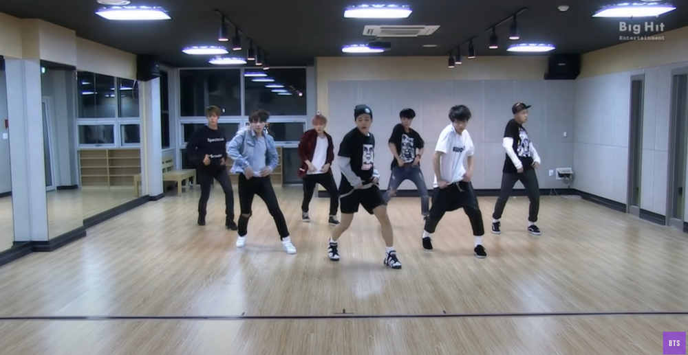 Group dancing in spacious studio with wooden floor.