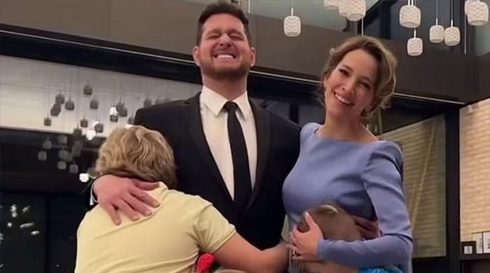 Smiling couple hugging children indoors.