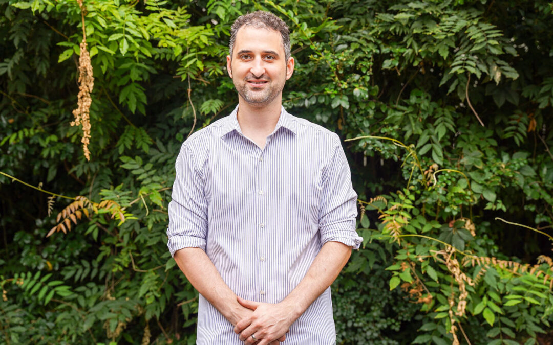 Man smiling in front of leafy background