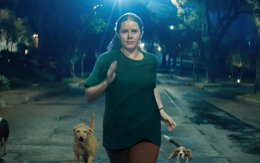 Woman running at night with dogs on street.