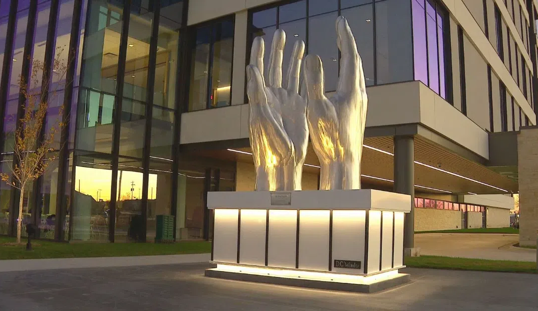 Silver hands sculpture outside modern building