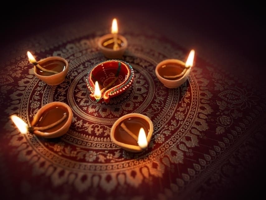 Diwali lamps arranged on decorative red fabric.