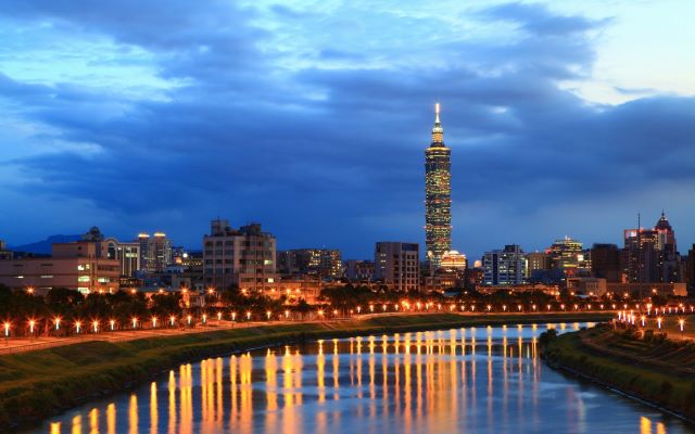 Taipei skyline at night with illuminated skyscraper.