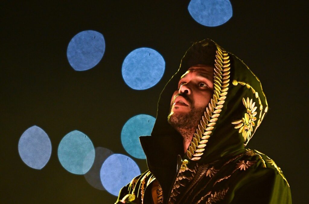 Person in ornate robe under colorful lights at night.