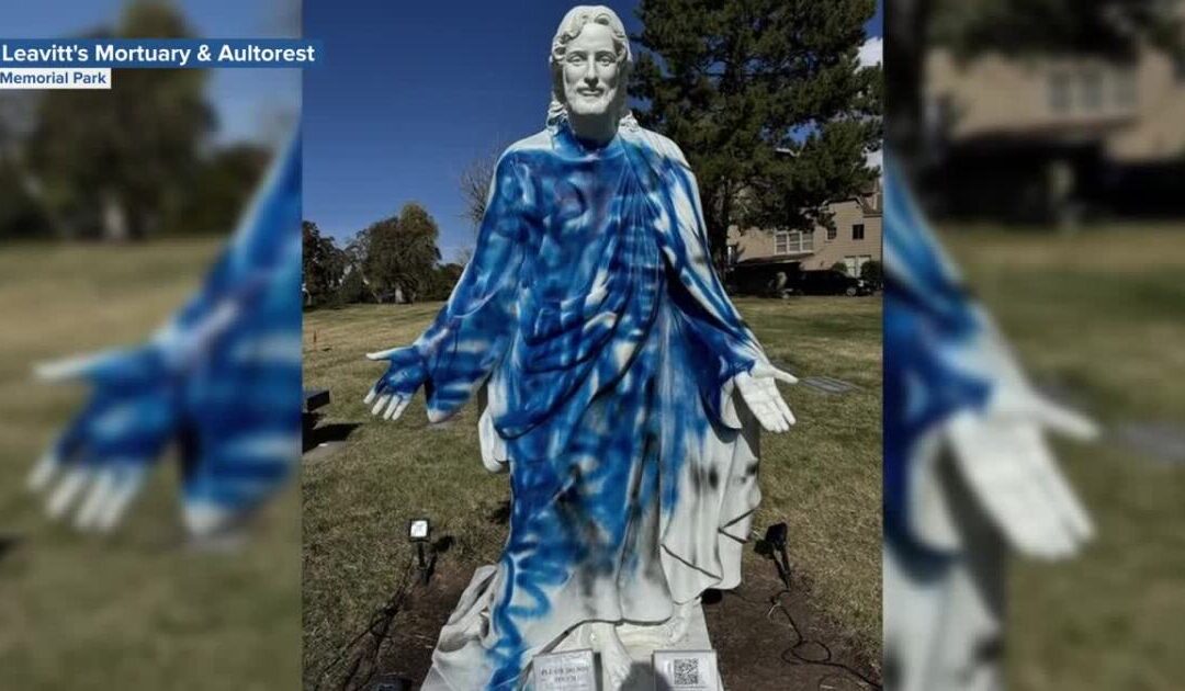 Vandalized statue with blue spray paint in park.